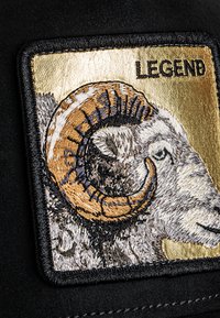 Embroidered patch featuring a ram's head with golden horn accents on a textured black background, labeled "LEGEND" in black lettering.