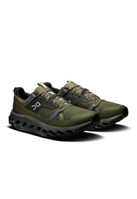 Olijfgroene sportschoenen met een bovenwerk van mesh en synthetisch materiaal, met een dikke, gestructureerde zool en reflecterende accenten. Veters en een gevoerde kraag.