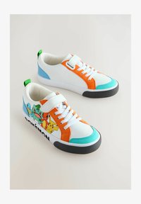 Zapatillas blancas con acentos en naranja, azul y verde. Presentan personajes de Pokémon en el lateral. Suela de goma y correa de velcro ajustable.
