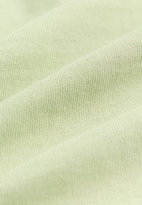 Lysegrønt tekstureret stof med fint ribmønster, der fremviser bløde, glatte linjer og en diskret glans. Velegnet til beklædning eller polstring.