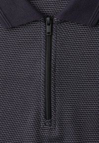 Close-up of black and white textured fabric with short zipper and ribbed dark collar on a garment.
