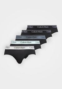 Πέντε ζευγάρια μαύρα εσώρουχα Calvin Klein με ζώνες μέσης σε λευκό, ανοιχτό μπλε, γκρι και δύο αποχρώσεις του μαύρου, τοποθετημένα σε εναλλασσόμενη σειρά.