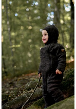 Textured dark gray hooded jumpsuit with a zipper, worn by a child holding a stick, set against a blurred forest background.