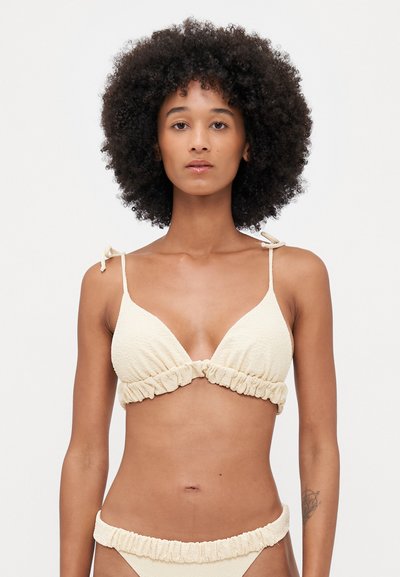 Ensemble de bikini beige avec un tissu texturé, haut triangulaire aux bords ondulés et bretelles ajustables, associé à un bas froncé assorti.