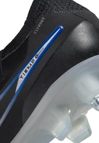 Schwarzer Fußballschuh mit Flyknit-Obermaterial, blauen und silbernen Akzenten sowie einer durchsichtigen Sohle mit geformten Stollen für Traktion.