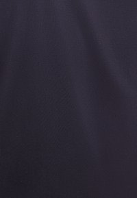 Tessuto blu navy con una texture liscia e opaca. Il materiale sembra elastico e leggero, mostrando sottili variazioni alla luce.