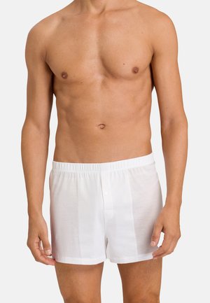 Boxers en coton blanc avec une ceinture élastique et un unique bouton. Texture lisse, coupe à mi-cuisse, et sans motifs visibles.