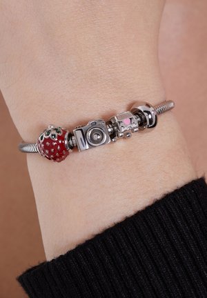 Silver charm bracelet featuring a red enamel strawberry, silver camera, decorative spacer, and a smooth silver bead with a heart detail.