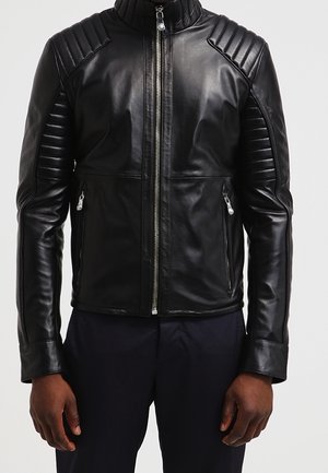 Black leather biker jacket with quilted shoulder and sleeve panels, front zipper, and zippered side pockets worn by person.