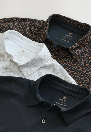 Trii ovratne polo majice: crna majica, bijela majica s geometrijskim zlatnim uzorcima i tamnoplava majica. Sve imaju dugmad.