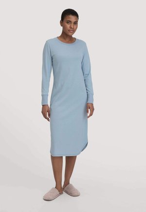Camicia da notte azzurro chiaro a maniche lunghe realizzata in tessuto morbido, con scollatura rotonda e spacchi laterali. Il modello indossa pantofole grigie con texture.