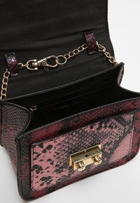 Mini borsa a tracolla con un motivo in pelle di serpente rosa e nera, hardware dorato, tracolla a catena e fodera interna nera con tasca con zip.