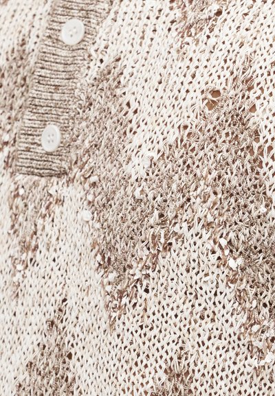 Κοντινό πλάνο σε μπεζ και καφέ πλεκτό ύφασμα με υφασμένα διαμαντένια σχέδια και δύο λευκά κουμπιά σε ριμπ ύφανση.