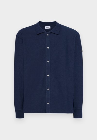 Camicia a maniche lunghe blu navy in tessuto morbido, con colletto a punta, chiusura frontale con bottoni e un piccolo logo sulla manica.