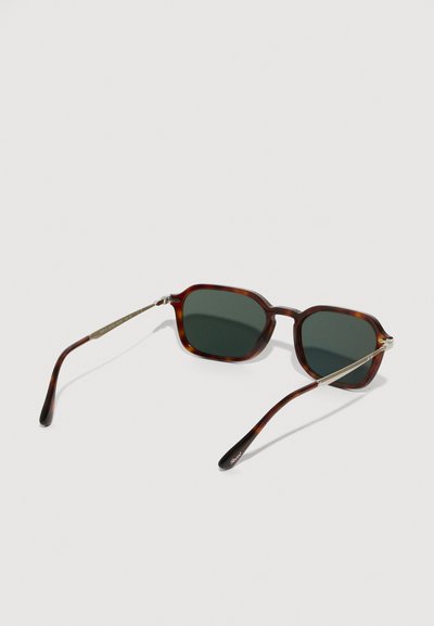 Sunglasses iz tortoiseshell rektangularne oblike z temno zelenimi lečami in tankimi srebrnimi zamkami, nagnjene na beli površini.
