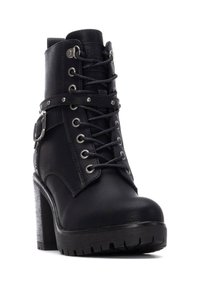 Bota de tobillo de cuero negro con un alto tacón bloque, cierre de cordones en la parte frontal, acentos metálicos y una correa decorativa con tachuelas. Suela de goma texturizada.