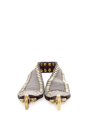 Coppia di cinturini in pelle scura decorati con file di piccoli borchie rotonde in ottone e grandi anelli in ottone alle estremità.