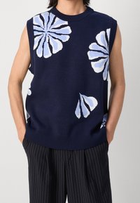 Marineblauer Strickpullover ohne Ärmel mit blauen Blumenmustern. Verfügt über einen gerippten Halsausschnitt und Saum sowie eine strukturierte Stoffoberfläche. Wird über Nadelstreifenhosen getragen.