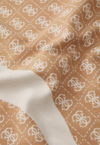 Beżowy materiał z powtarzającym się białym wzorem logo w kształcie diamentów. Tkanina ma miękką teksturę z kontrastującymi białymi akcentami.
