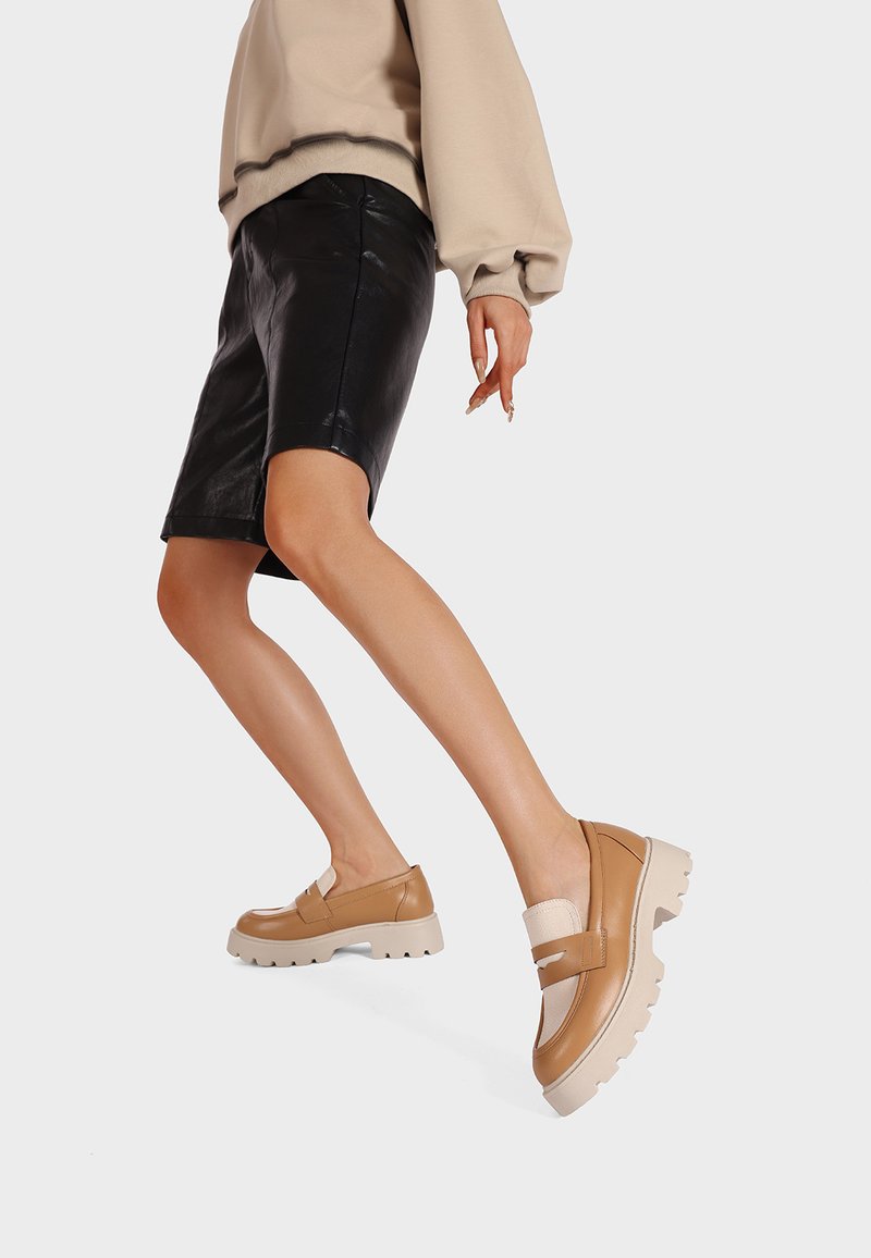 Scarpe slip-on color beige con suole spesse color crema, caratterizzate da una finitura in pelle liscia e dettagli elastici per un look casual.