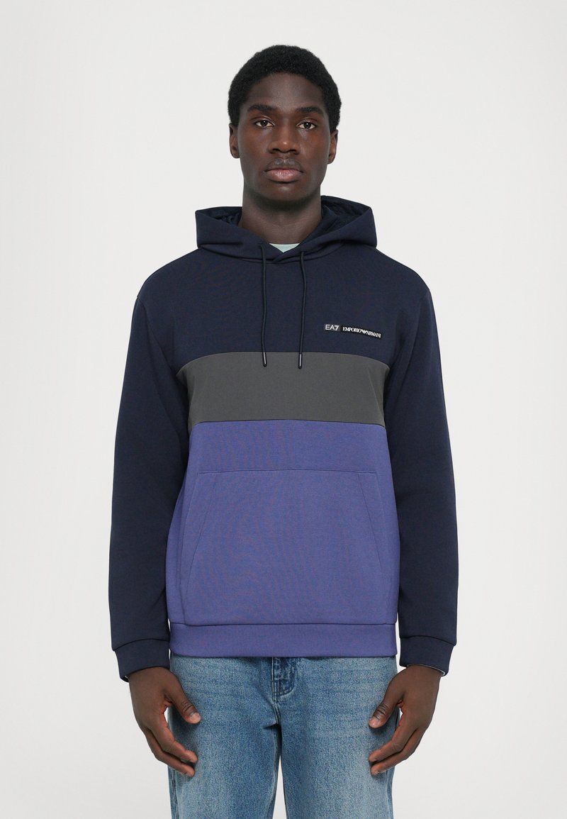 Sweatshirt azul marinho e cinza em tecido misto, com bolso canguru frontal, capuz com cordão e design de blocos de cor horizontal.