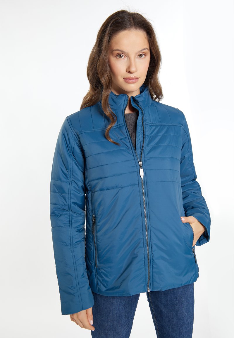 Giacca isolata blu con colletto alto e chiusura con cerniera. Presenta linee orizzontali cucite e due tasche laterali con cerniere.