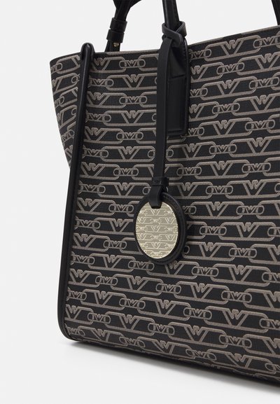 Svart tote bag med gjentagende grå logo-mønster, skinnkanter og en rund metallisk anheng. Har en strukturert form og teksturert stoff.