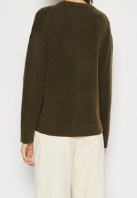 Grön stickad tröja med rund halsringning, sänkta axlar och avslappnad passform. Ribbad fåll och ärmslut; mjuk textur.