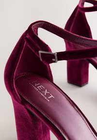 Bordó semišové sandály na vysokém podpatku s kotníkovými pásky a blokovým podpatkem, značky "NEXT Forever Comfort", velikost 40, na světlém pozadí.