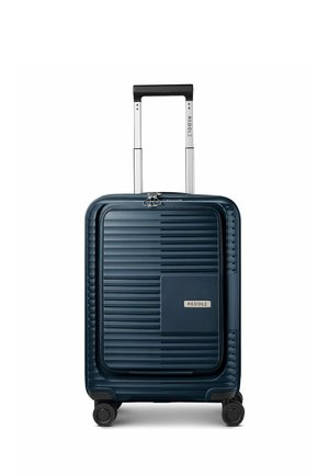 Valise rigide bleu foncé avec face avant texturée, quatre roues, une poignée télescopique et un compartiment avant zippé portant l’étiquette Redolz.
