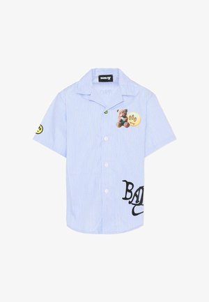 Lichtblauw overhemd met korte mouwen en knopen, met dunne witte strepen, beren- en pootafdrukken op de borst, een glimlachend gezicht op de mouw en de tekst "BAD" nabij de zoom.