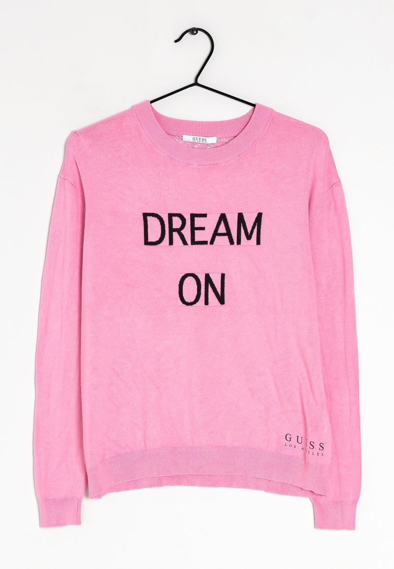 Suéter rosa con cuello redondo que presenta 'DREAM ON' en letras negras. Incluye puños y dobladillo acanalados. Logo de GUESS en la parte inferior izquierda.