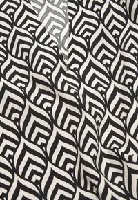 Cotton fabric featuring a geometric black-and-white pattern with overlapping leaf shapes and sharp angles, smooth texture, and a matte finish.