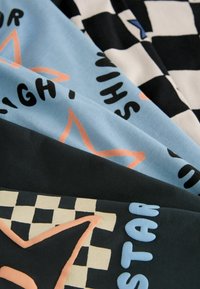 Kleurige stof met blauwe, zwarte en crèmekleurige tinten. Patroon omvat een dambord en grote sterren met zwarte tekst en roze accenten.