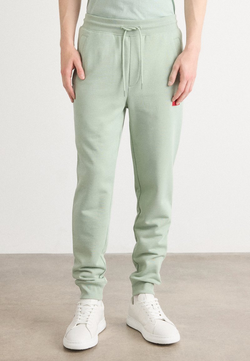 Pantalones de chándal de color verde claro, hechos de una suave mezcla de algodón, con una cinturilla elástica y cordón, además de bolsillos laterales.