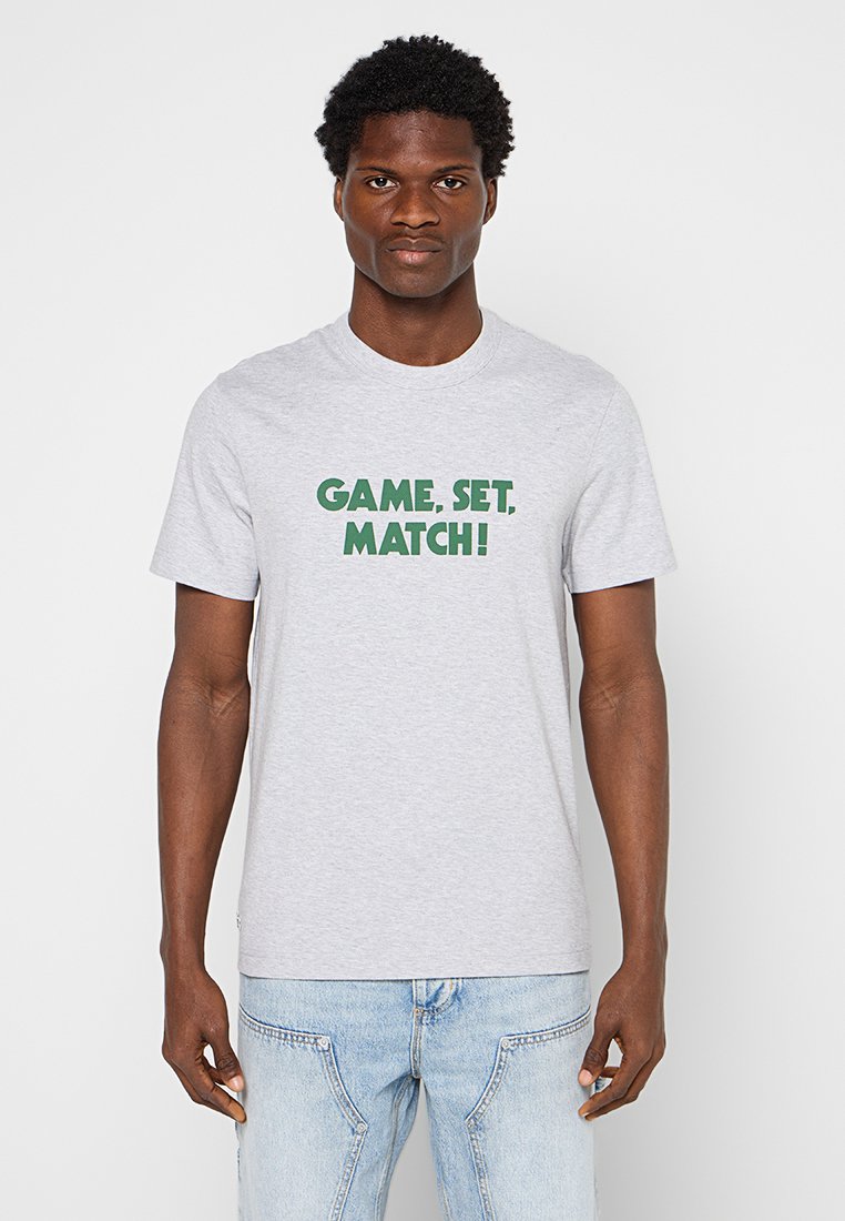 Graues Baumwoll-T-Shirt mit fettem grünen Text "GAME, SET, MATCH!". Crew-Ausschnitt und kurze Ärmel. Einfaches Design, lässige Passform.