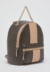 Sac à dos en simili cuir noir et marron avec motif géométrique, bande verticale beige, ferrures dorées et fermetures éclair doubles sur la poche avant.