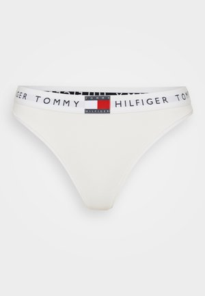 Vit bomullsstringtrosor med ett elastiskt midjeband i svart och vitt med en liten färgad logopatch framtill.