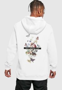 Sudadera blanca con un gráfico de flores y mariposas en la parte posterior y el texto "DATE TIEMPO A TI". Puños y cinturilla acanalados.