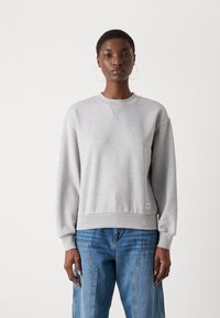 Sweatshirt grigio chiaro con collo a giro, polsini e orlo a costine, realizzato in tessuto morbido con un piccolo etichetta del logo in basso a sinistra.