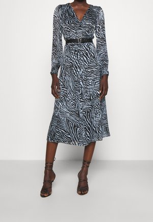 Abito a strisce zebrate in blu e nero, tessuto setoso, maniche lunghe, scollatura a V, vita cinchata con una cintura nera e gonna di lunghezza media.