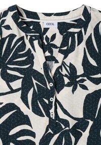 Chemise avec imprimé botanique bleu foncé sur fond beige, avec un col rond et trois boutons blancs sur la patte de boutonnage avant.