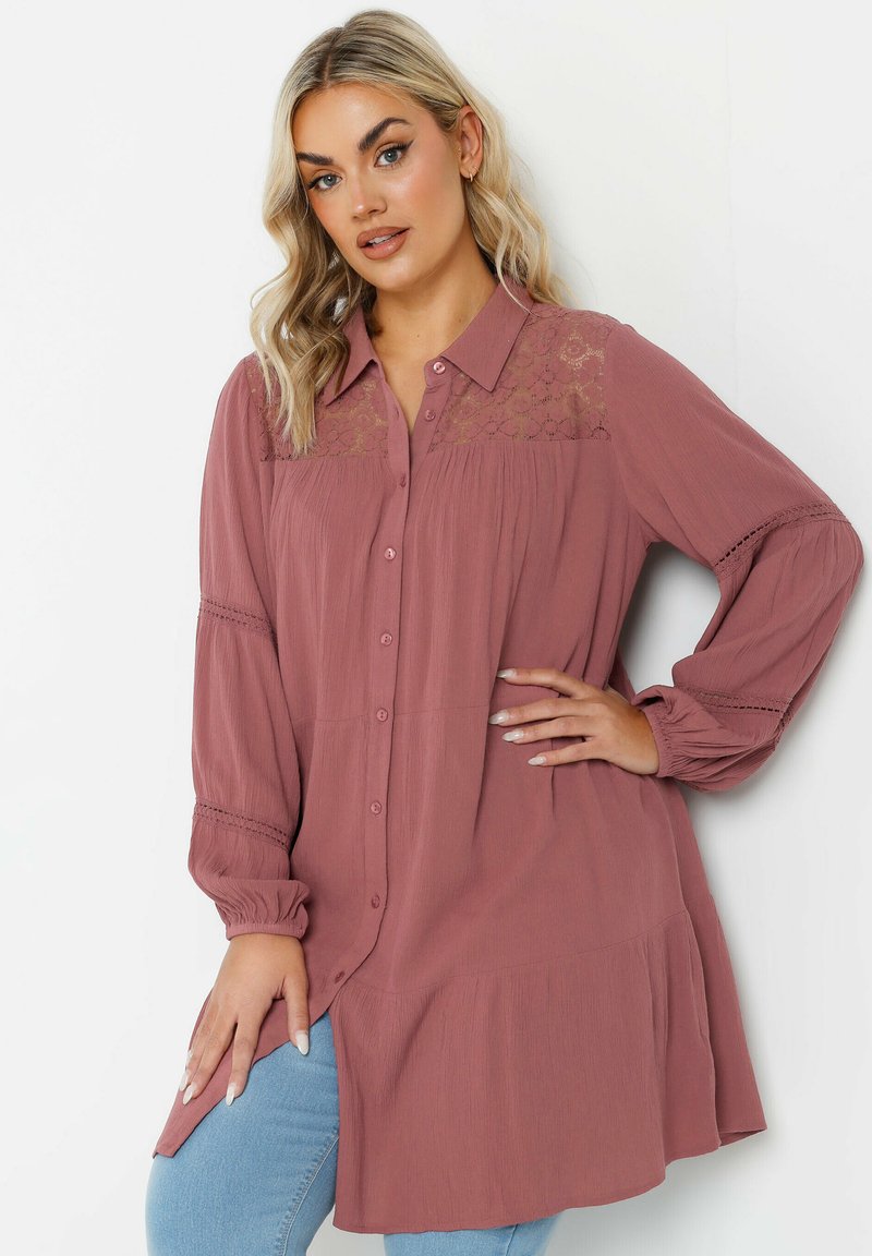 Camisa de manga larga, abotonada en rosa empolvado con detalles de encaje en los hombros y mangas fruncidas. Tejido suave y texturizado con un corte relajado.