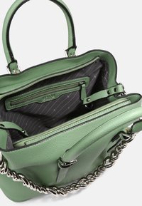 Zelená kožená taška na rameno s otevřeným vrchem, se černobílým proužkovaným podšívkou, zipovou kapsou a stříbrným řetízkem na popruhu.