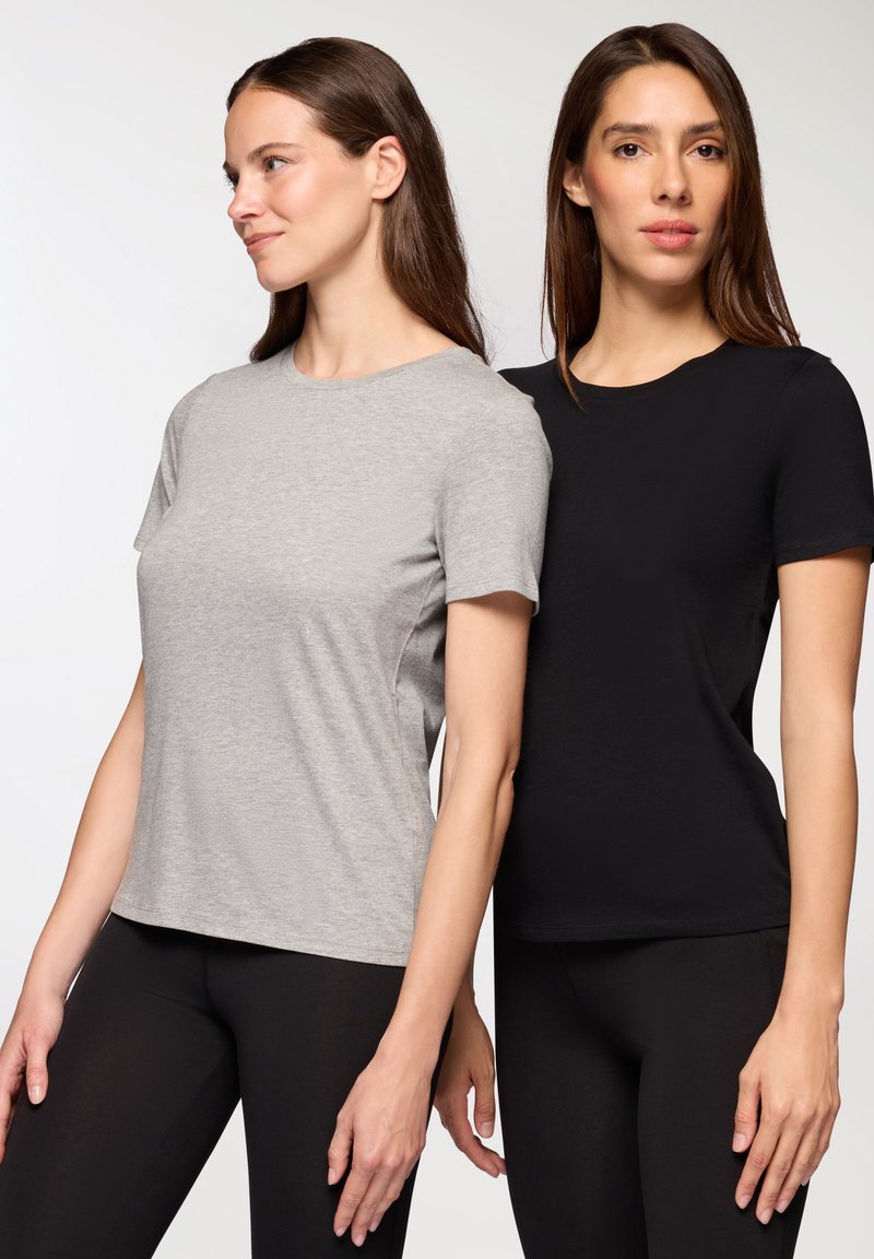 Dwie krótko rękawowe koszulki w kolorze szarym i czarnym z bawełny. Obie mają okrągły dekolt i sięgają w biodra, połączone z czarnymi legginsami.