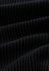 Schwarzer gerippter Stoff, der eine weiche Textur zeigt und tiefe Rillen sowie ein einheitliches Muster aufweist, ideal für Kleidung oder Polsterung.