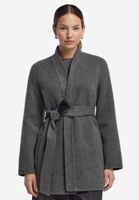 Grå ullblandning omslagsoverall med ett knytbälte, slagkrage och två framfickor. Slät textur och något A-linjeformad design.