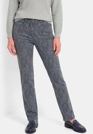 Femme portant un pantalon droit gris à motifs, associé à un pull à côtes gris clair et des mocassins bleu foncé.