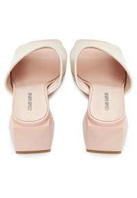 Paire de mules en cuir rose pâle à talons blocs ouverts à l'avant, avec des talons géométriques carrés, nom de la marque sur la semelle intérieure, vue de dos.
