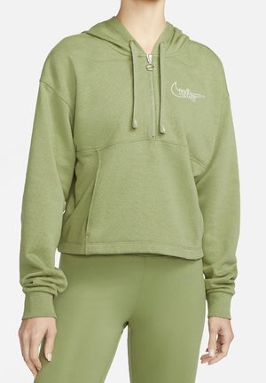 Person trägt hellgrünen, kurz geschnittenen Hoodie mit Frontreißverschluss und Kordeln, kombiniert mit passenden grünen Leggings.